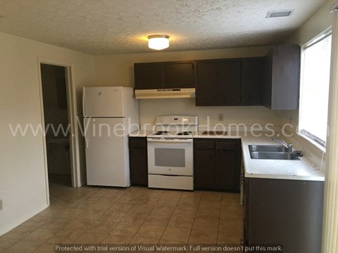 A kitchen with a white refrigerator, black cabinets, and a tiled floor.