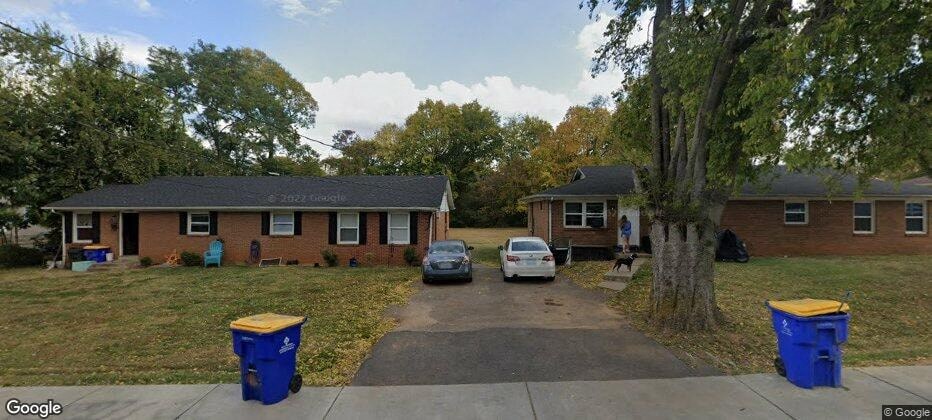 a house with a tree and cars parked in front of it