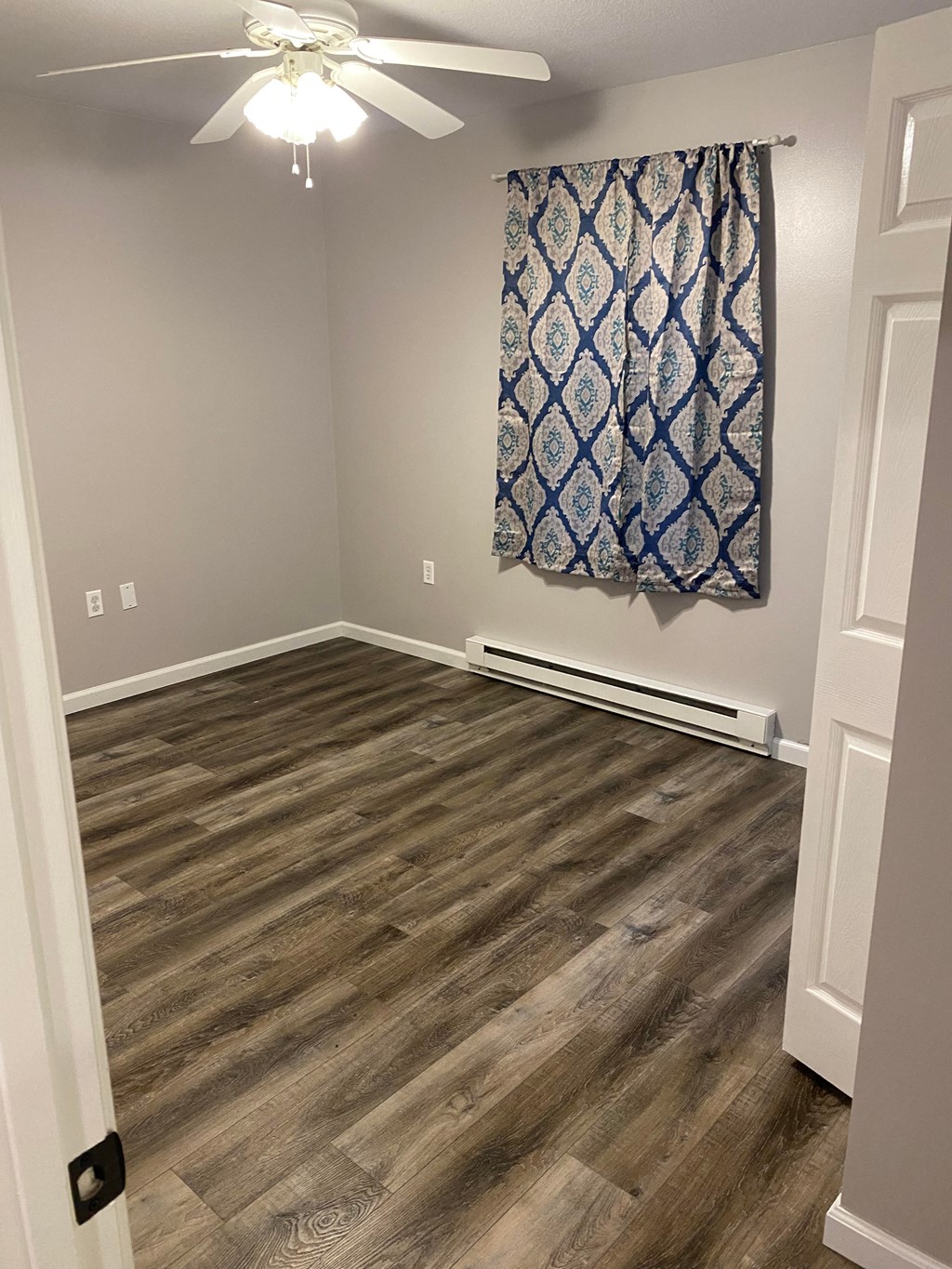 a living room with wood flooring and a curtain on the wall