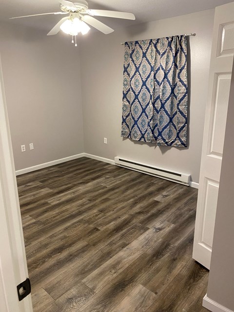 a living room with wood flooring and a curtain on the wall