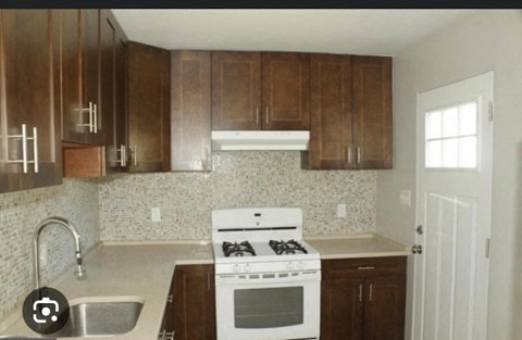 an empty kitchen with wooden cabinets and a white stove