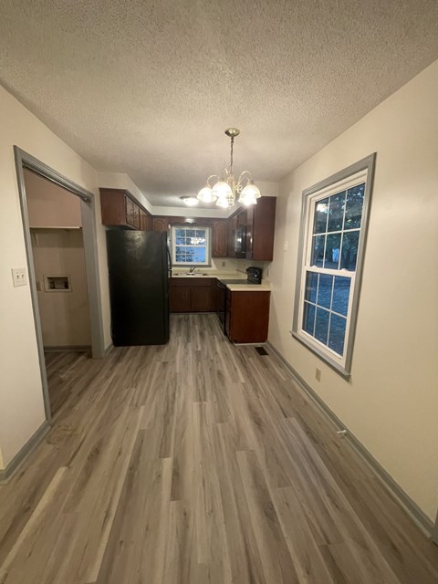 A kitchen with wood flooring and a black refrigerator.