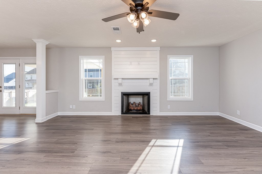 an empty living room with a fireplace and a ceiling fan