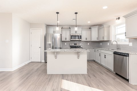 a renovated kitchen with white cabinets and a large island