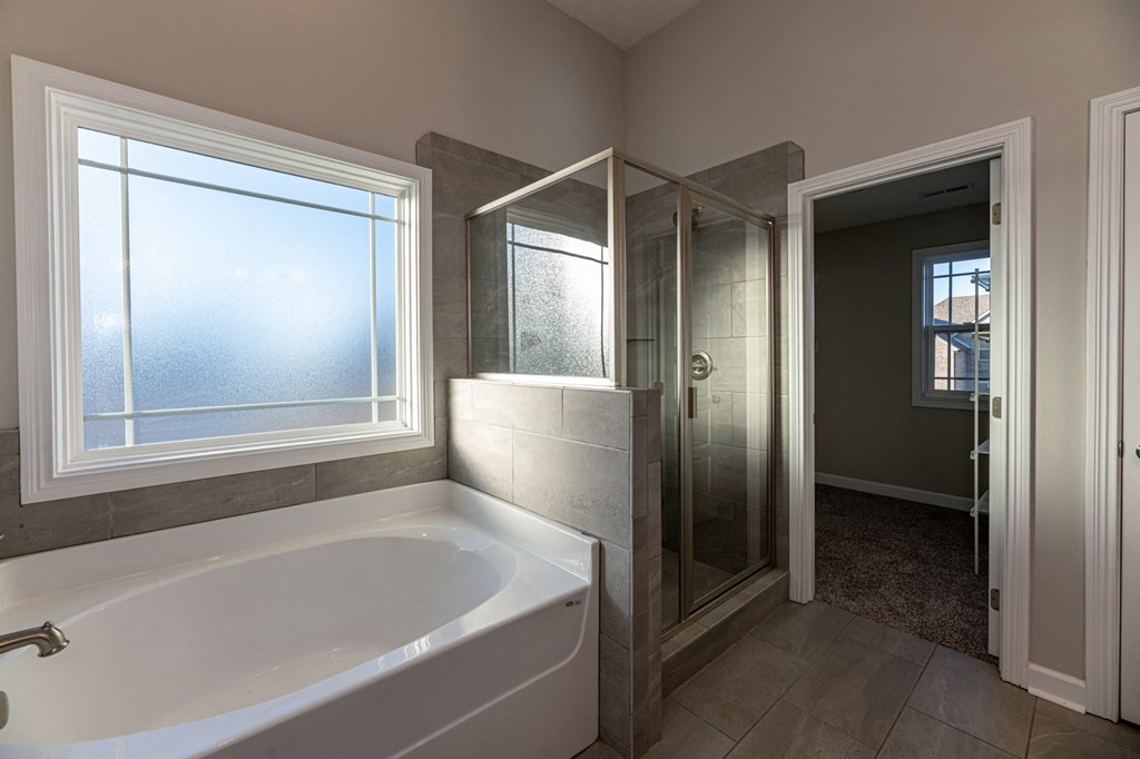 a bathroom with a tub and a shower and a window