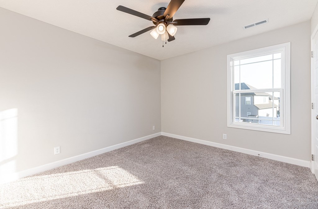 an empty living room with a ceiling fan and a window