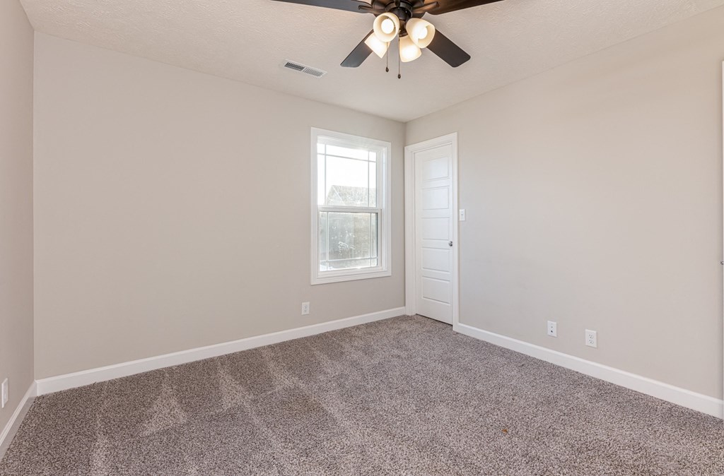 an empty living room with a ceiling fan and a window