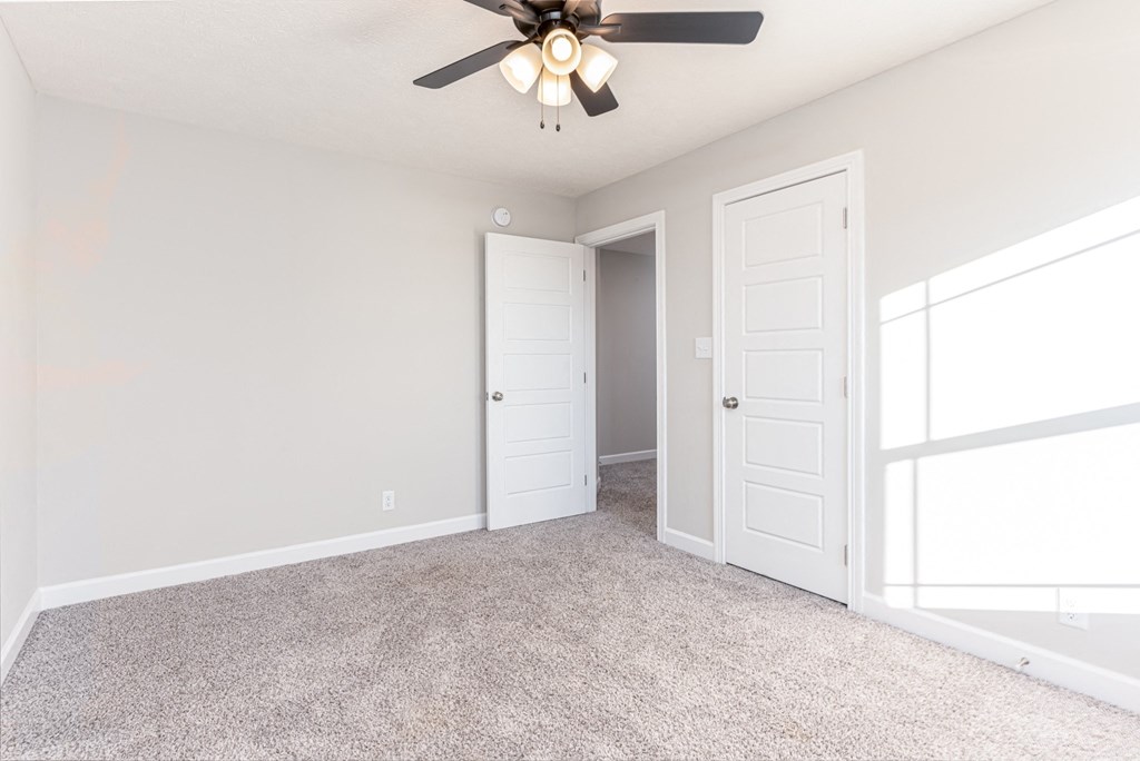 an empty bedroom with a ceiling fan and a closet