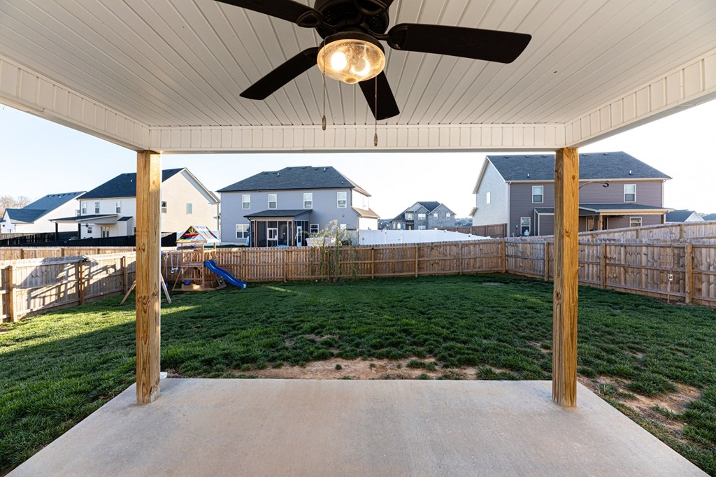 a covered patio with a ceiling fan and a yard with a fence