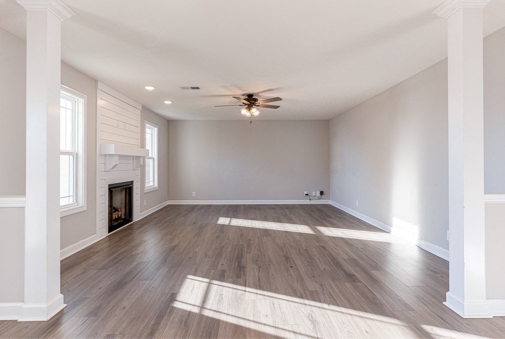an empty living room with a ceiling fan and a fireplace