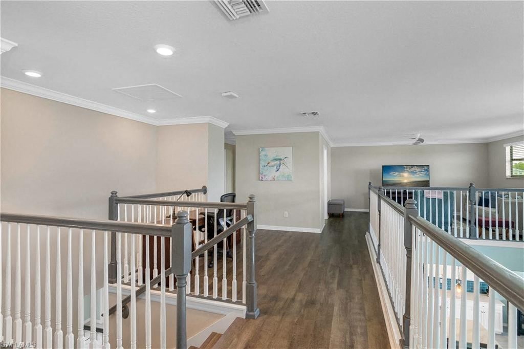 the upstairs lobby of a house with a staircase and a room with a couch