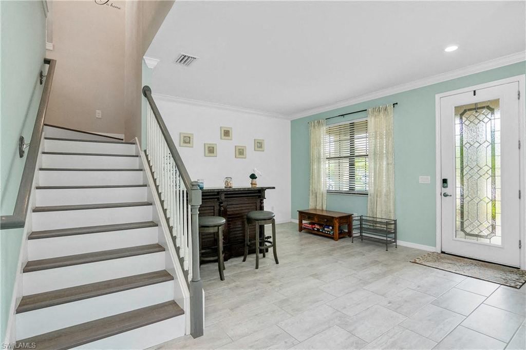 the entryway of a house with a staircase and a table and chairs