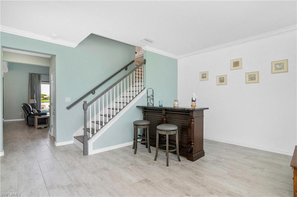 a living room with a staircase and a bar with three stools