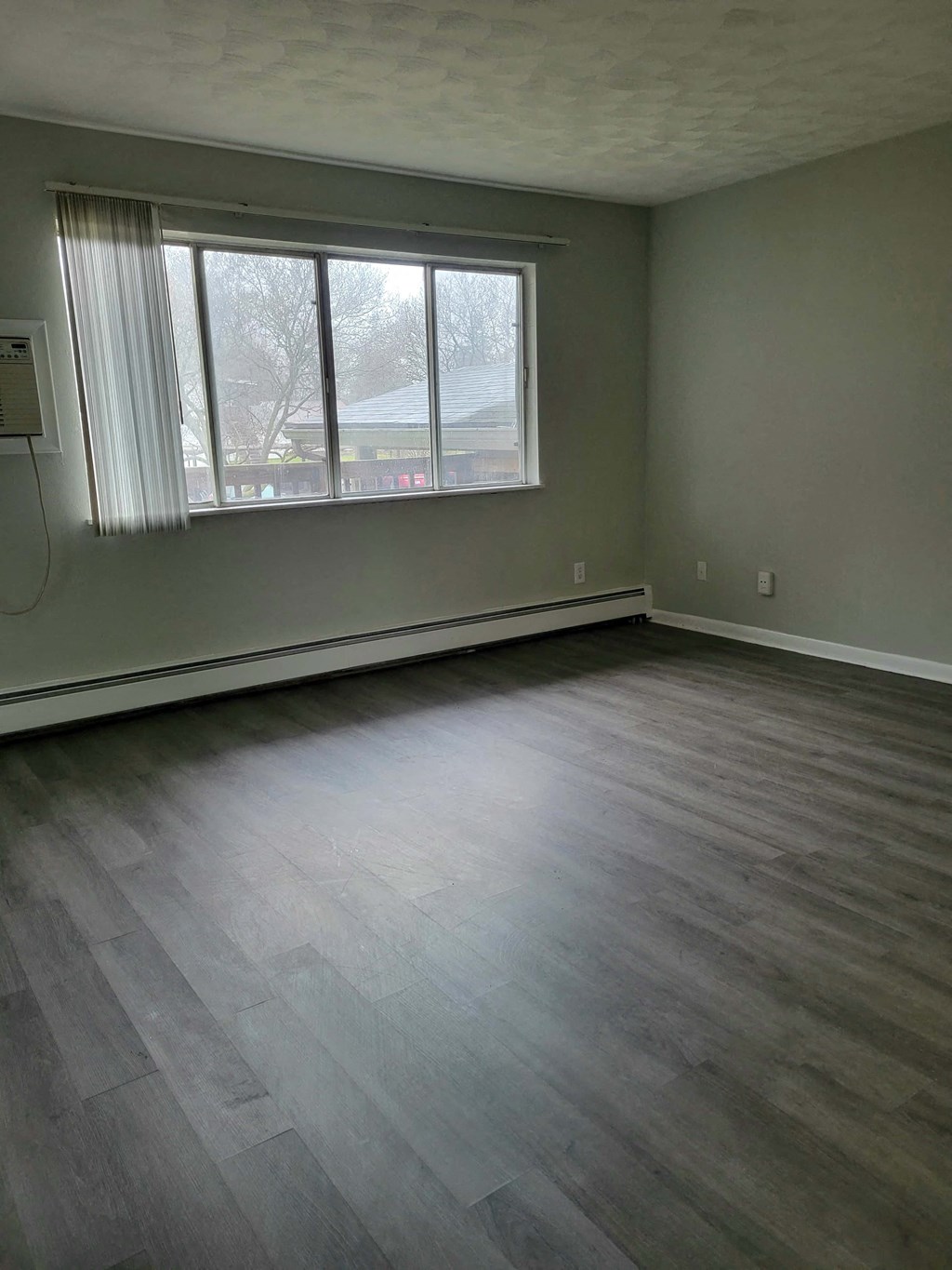an empty living room with wood floors and a window