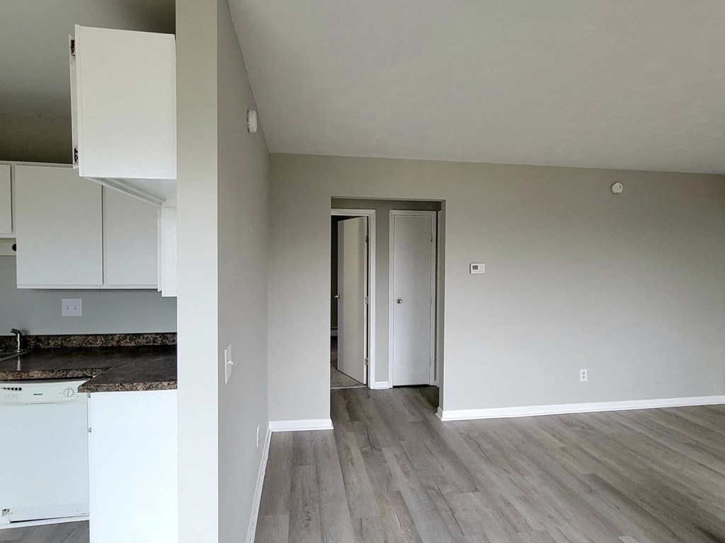 a renovated kitchen with white cabinets and a door to a hallway