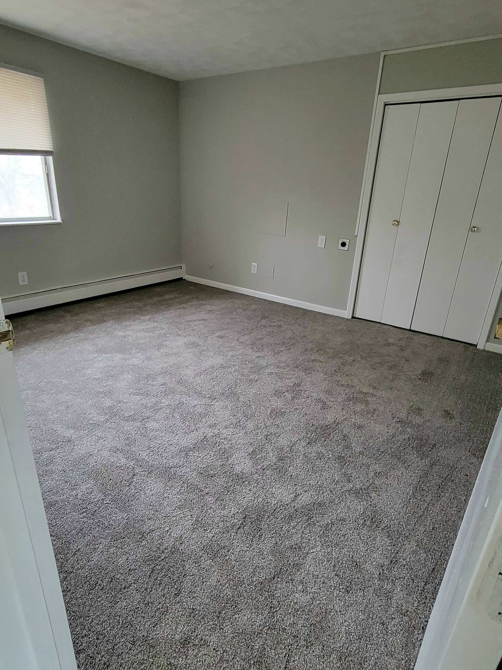 a carpeted room with white cabinets and a window