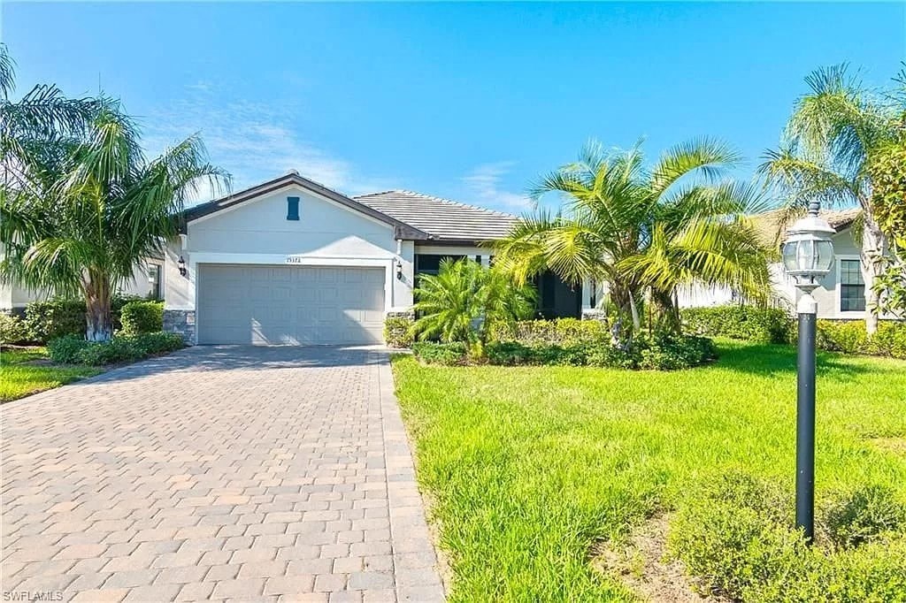 a house with a driveway and palm trees in front of it
