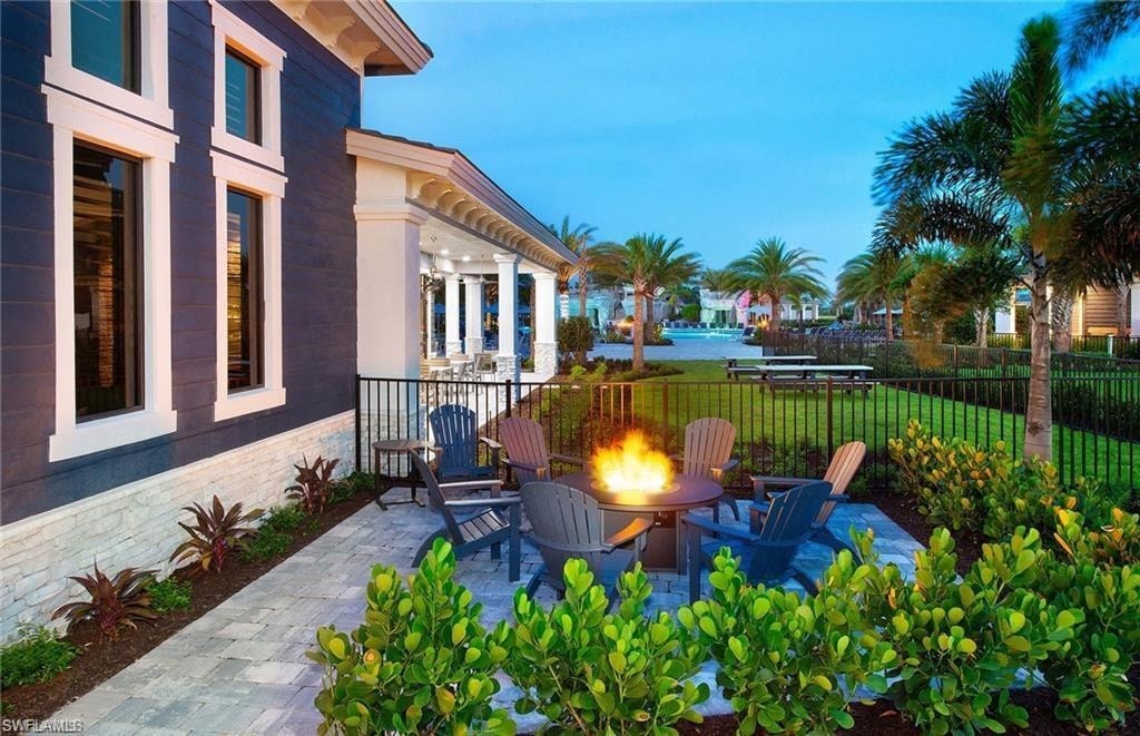a patio with a fire pit and chairs in front of a house