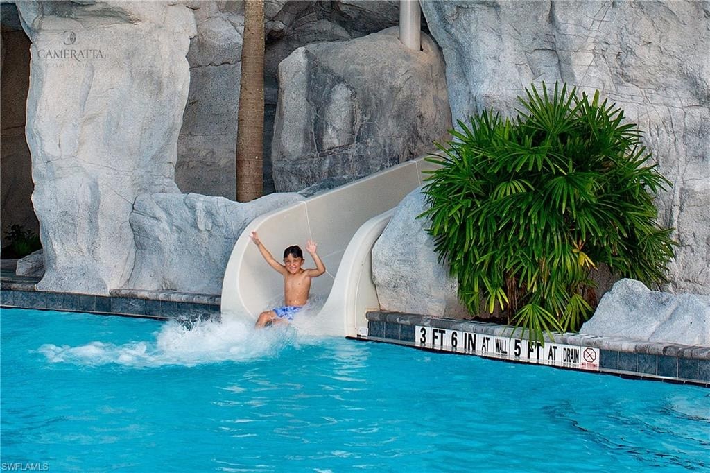 a man is going down a water slide in a pool