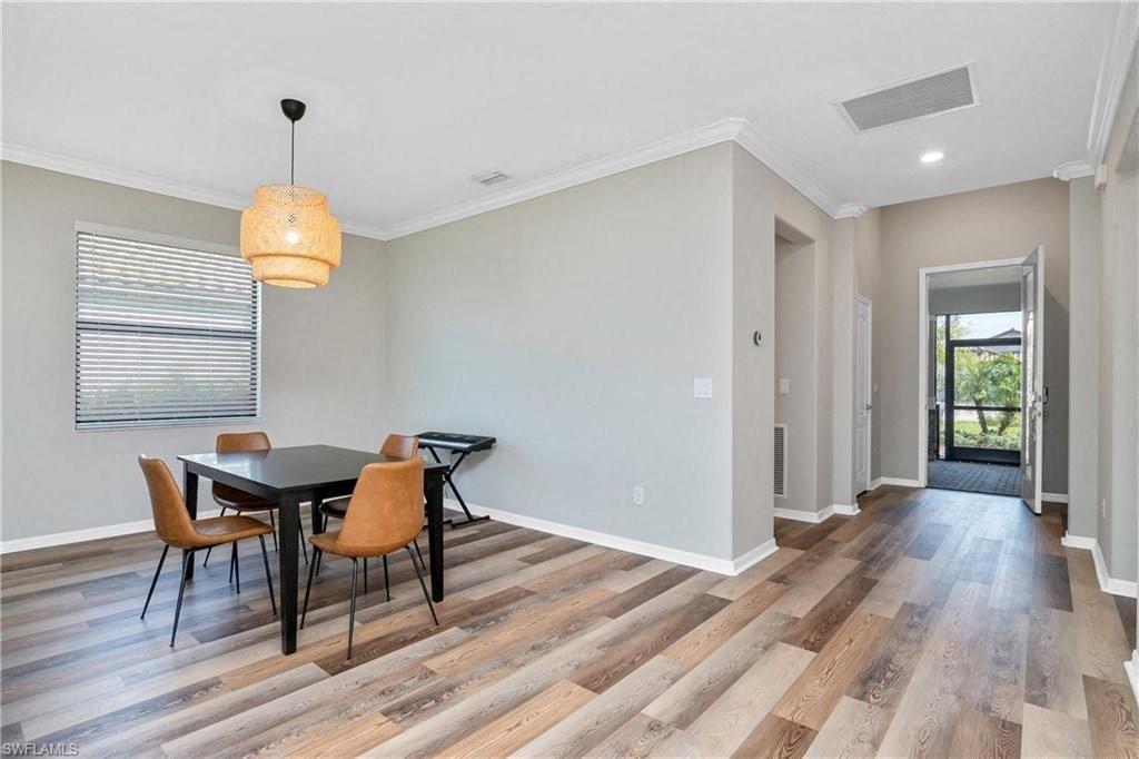 a dining room with a table and chairs and a door to a hallway
