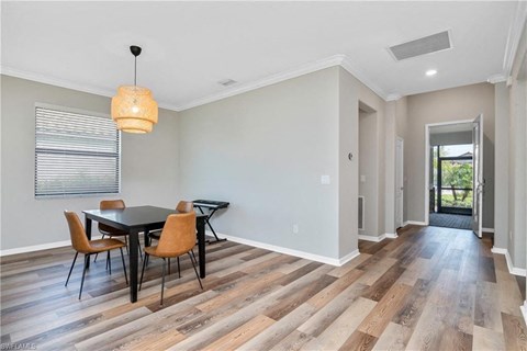 a dining room with a table and chairs and a door to a hallway