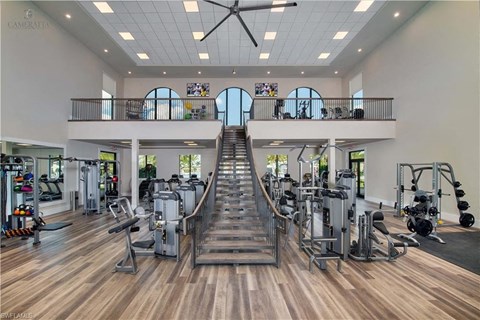 a gym with cardio machines and a staircase in the middle