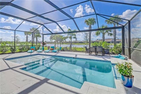 the pool is under a glass roof with chairs around it