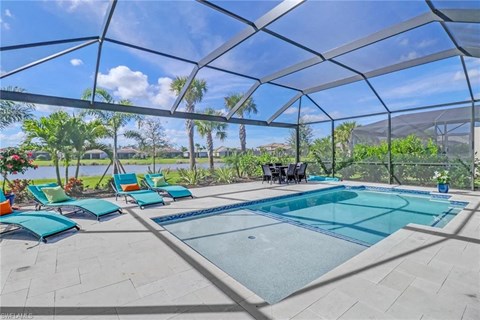 the pool is under a glass roof with chairs around it