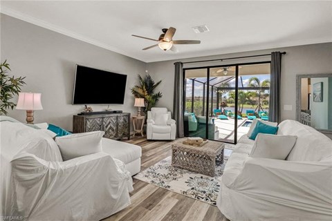 the living room has a large screen tv and sliding doors to the pool