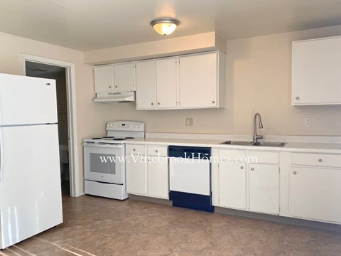 A kitchen with white appliances and cabinets.