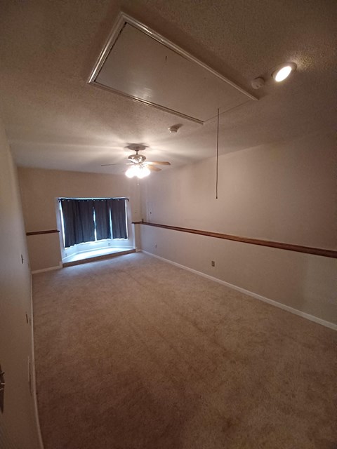 an empty room with a ceiling fan and a window