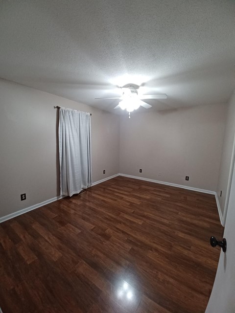 a living room with wood floors and a ceiling fan