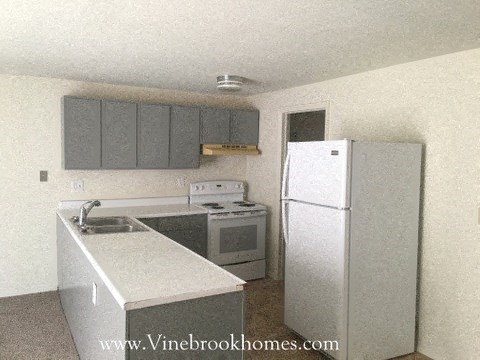 A kitchen with a white fridge and a white sink.