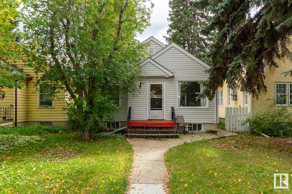 a white and yellow house with a red bench in front of it