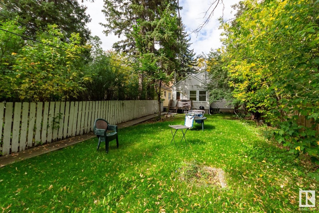 a backyard with a fence and a lawn with chairs and a table