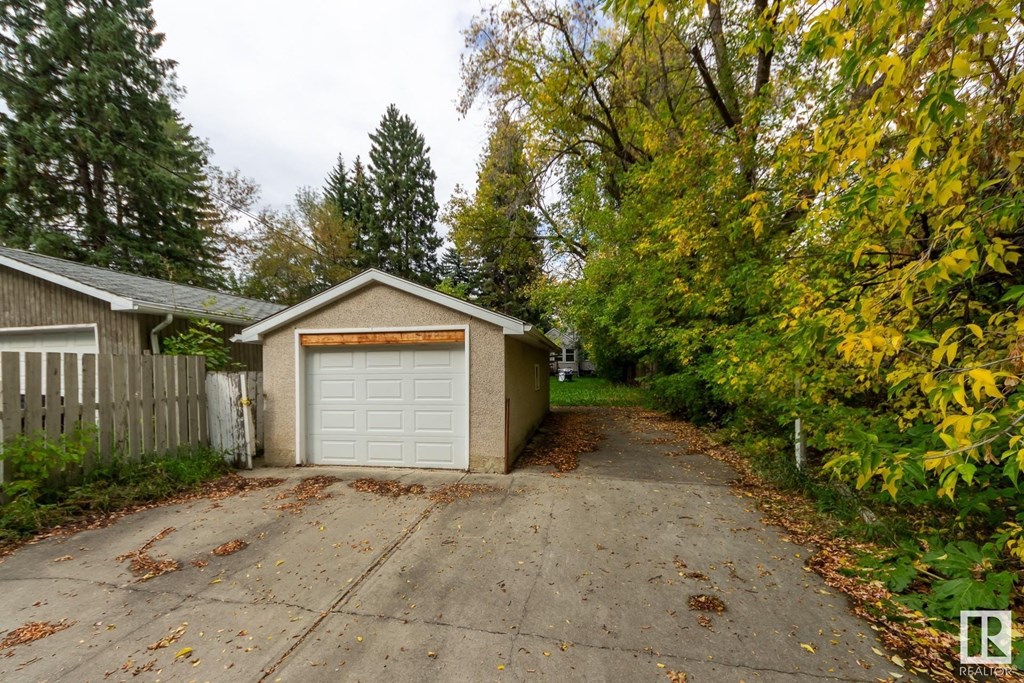 a small garage with a white garage door on the side of a driveway