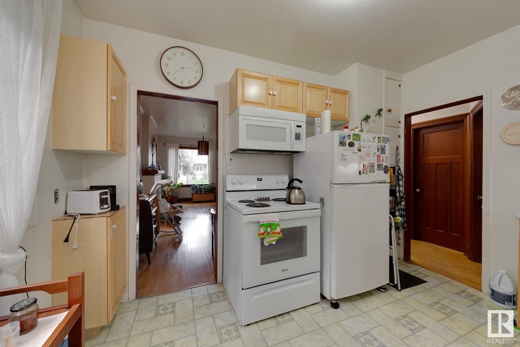 a kitchen with white appliances and a clock on the wall