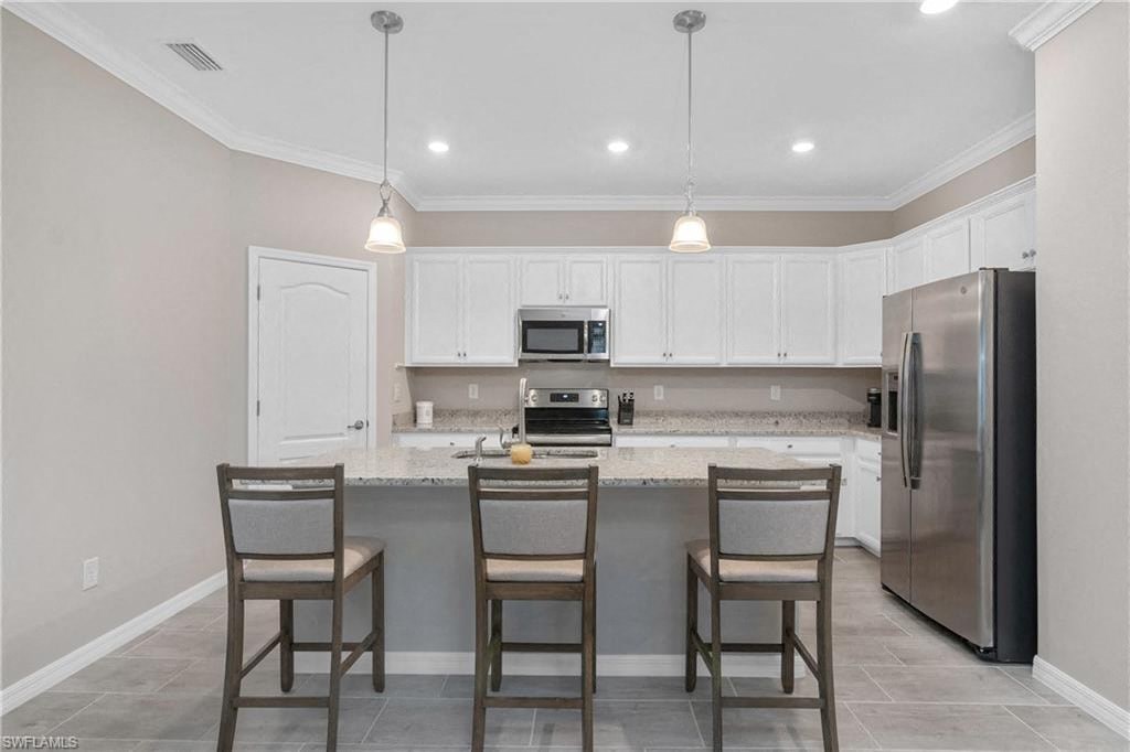 a kitchen with a bar with three chairs