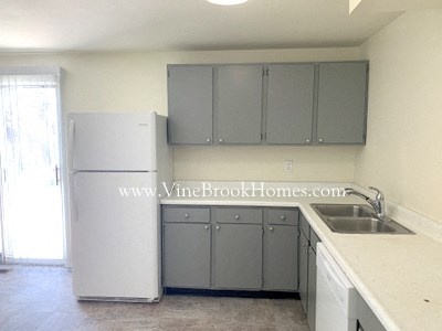 A kitchen with a white fridge, cabinets and sink.