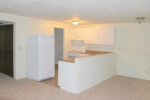 A white refrigerator sits in a kitchen with white cabinets.