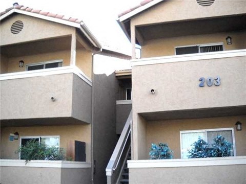 Two tan buildings with the number 203 on the side of the right one.