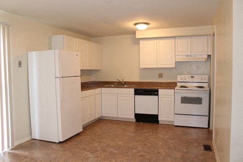 a kitchen with white cabinets and appliances and a white refrigerator