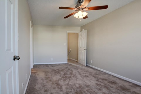 A room with a ceiling fan and carpeted floor.