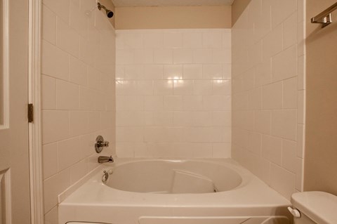 A white bathroom with a tub and toilet.