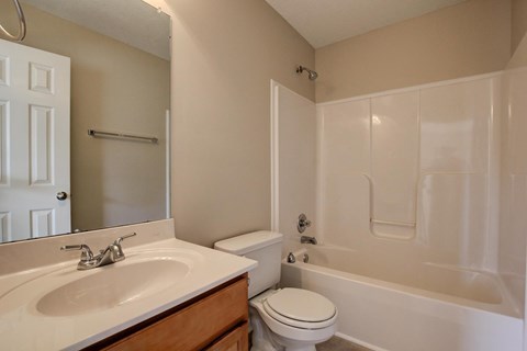 A white toilet sits next to a white bathtub in a bathroom.