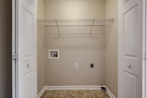 A small, empty room with a wire shelf and a picture frame on the wall.