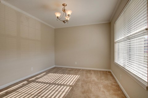 A room with a chandelier and a window with blinds.