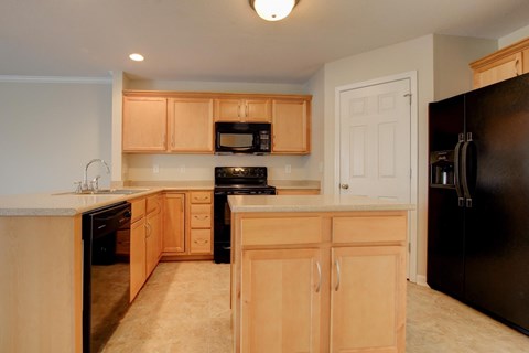 A kitchen with black appliances and wooden cabinets.
