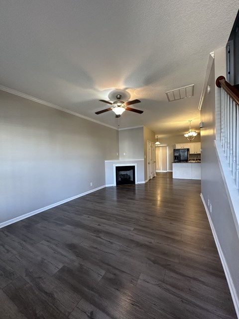 an empty living room with a ceiling fan and a fireplace
