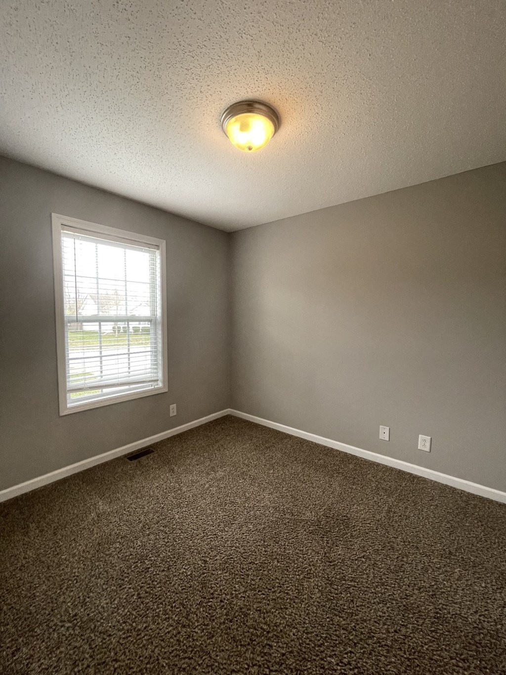 A room with a carpeted floor and a window.